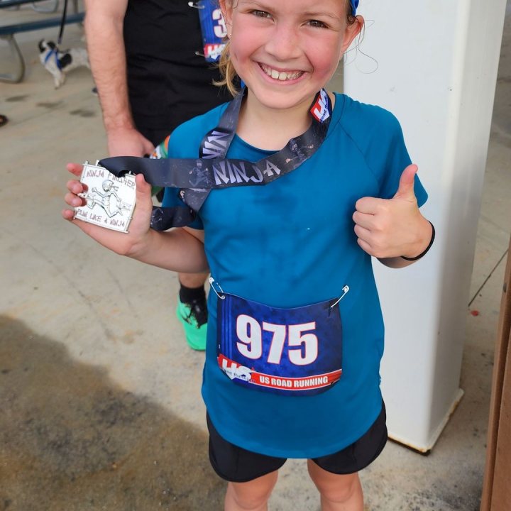 US Road Running race day photo with runners, walkers, finisher medals, and race staff