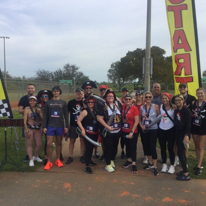 US Road Running race day photo with runners, walkers, finisher medals, and race staff