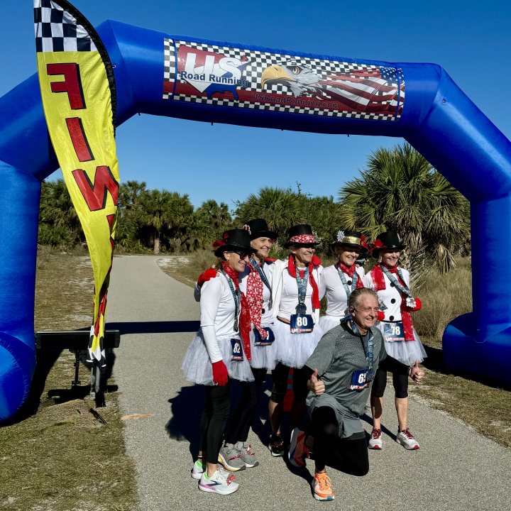 US Road Running race day photo with runners, walkers, finisher medals, and race staff