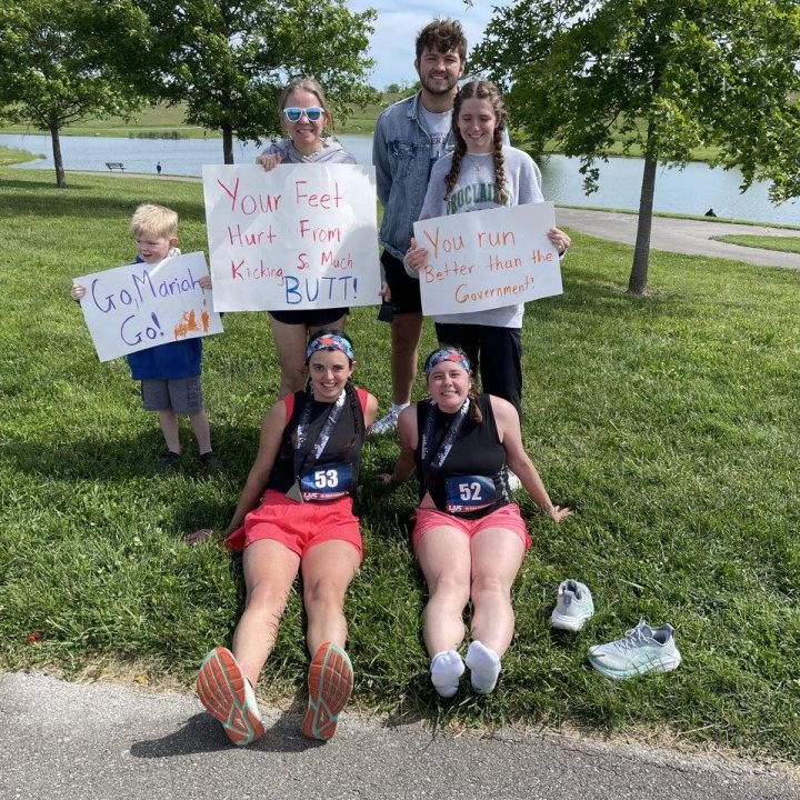US Road Running race day photo with runners, walkers, finisher medals, and race staff