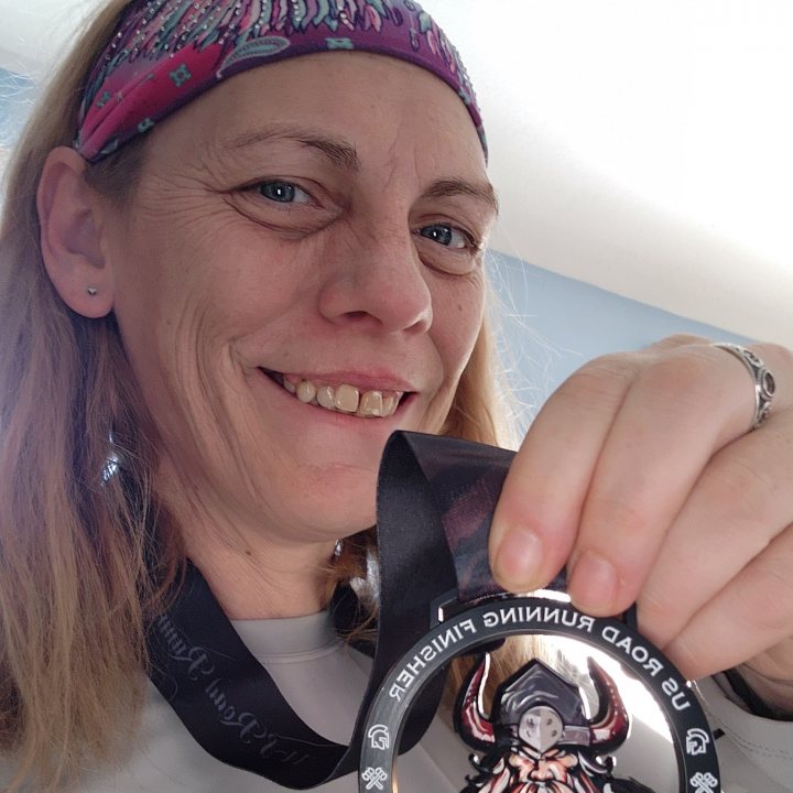 US Road Running race day photo with runners, walkers, finisher medals, and race staff