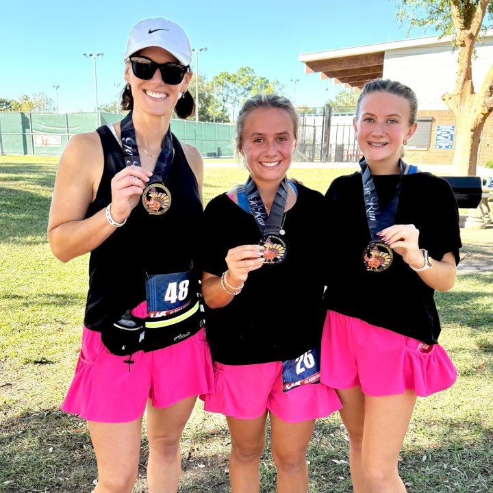 US Road Running race day photo with runners, walkers, finisher medals, and race staff
