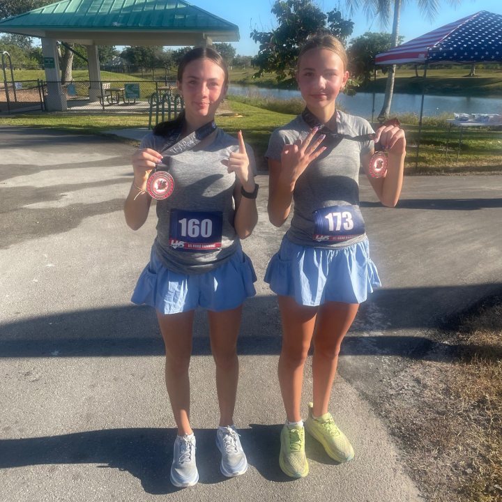 US Road Running race day photo with runners, walkers, finisher medals, and race staff